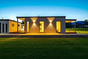 Osvětlená boční stěna tiny housu s okny za soumraku