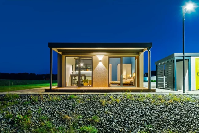 Tiny house zepředu večer s osvětlenou krytou terasou