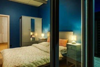 Ložnice tiny housu s rozsvícenými lampami, pohled přes okno za soumraku